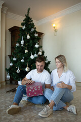 Happy young couple dancing near Christmas tree at home