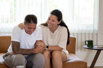 Obraz premium Adult lesbian couple comforting each other on couch at home