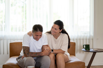 Adult lesbian couple comforting each other on couch at home