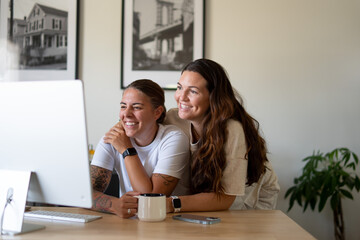 Obraz premium Adult lesbian couple use desktop computer in home office