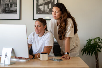 Obraz premium Adult lesbian couple use desktop computer in home office