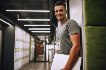 Joyous employee with the ID badge standing in the corridor