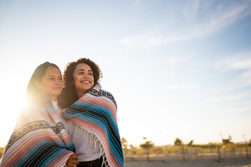 Hispanic lesbian couple uses blanket at beach