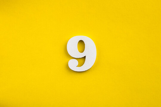 Number nine - white number in wood on yellow background