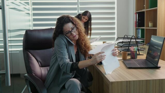 Business woman in office nervously waving her foot on a phone call being unhappy with business report. Woman calling a key client in office giving details of the trade.