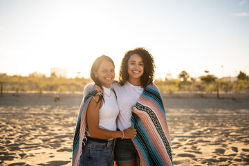 Fototapeta na wymiar Hispanic lesbian couple uses blanket at beach