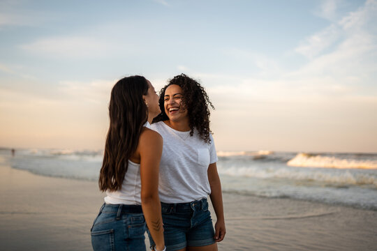 Hispanic lesbian couple stand by the ocean holding hands