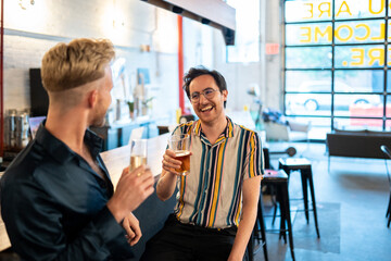 Two LGBTQ friends drink beer and champagne at a bar