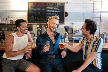 LGBTQ Friends sit at a bar with beer and champagne