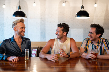 LGBTQ Friends sit at a bar with beer and champagne