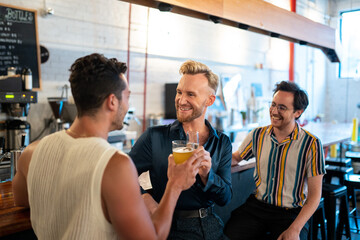 LGBTQ Friends sit at a bar and cheers beer and champagne