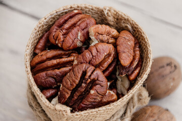 Close up of pecan nuts in brown sack on white wooden background