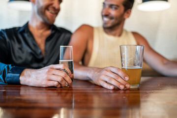 Two gay men hold glasses of beer and champagne