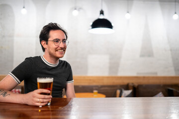 Bisexual man stands at a bar with beer