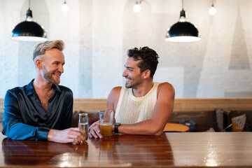 LGBTQ Friends sit at a bar with beer and champagne