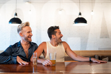LGBTQ Friends sit at a bar with beer and champagne