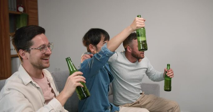 Three men sit on sofa watching football match