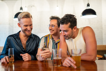 LGBTQ Friends sit at a bar and use a phone