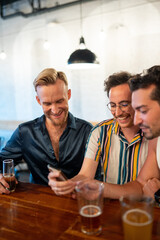 LGBTQ Friends sit at a bar and use a phone