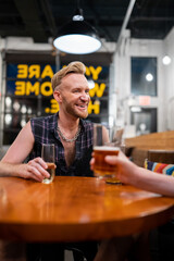 LGBTQ Friends sit at a bar with beer and champagne