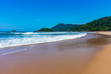 Paradise beach surrounded by rainforest and hills on a sunny day in Bertioga on the coast of Sao Paulo