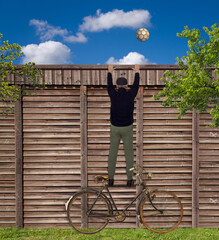 Fußball Fan klettert auf einen Holzzaun