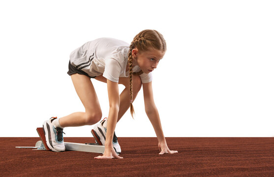 School age girl, junior runner or jogger at starting position ready to start a race. Concept of energy, action, motion, kids achievements