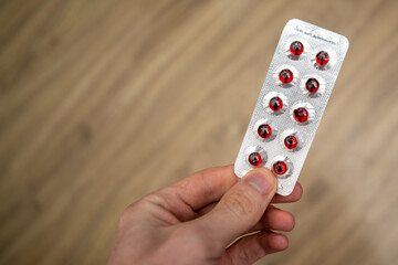 Red capsules in the package. Tablets in hand.