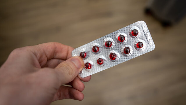 Red capsules in the package. Tablets in hand.