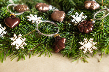 Live spruce branches with wooden snowflakes and glass toys of natural colors are laid out on craft paper