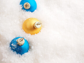 Blue and golden vintage Christmas baubles in the snow with space for text