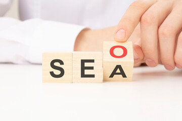 Hand flip SEO to SEA text wooden cube blocks on table background. search engine optimization,...