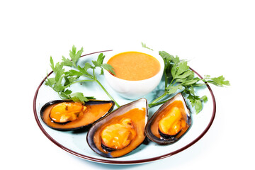 Dish with steamed mussels with parsley and a bowl of spicy sauce on a white background