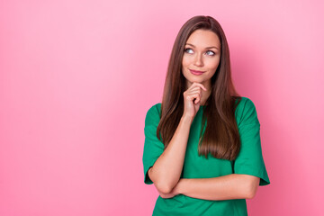 Portrait of gorgeous optimistic thoughtful girl wear green t-shirt hand on chin look empty space isolated on pink color background