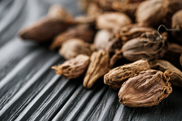 a barrel of dried black cardamom on a black wooden rustic background
