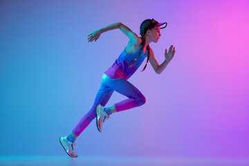 Running technique. Sportive girl, junior runner in stylish sportswear and cap posing isolated on...