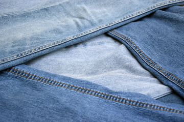 Lots of jeans pants in a stack. Denim background.