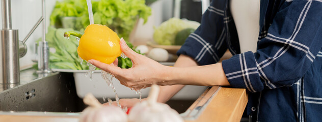 Close up hand of asian young housekeeper woman, washing sweet pepper, yellow paprika, vegetables...