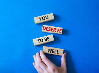 You deserve to be well symbol. Wooden blocks with words You deserve to be well. Beautiful blue...