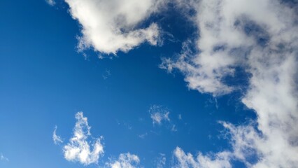 Blue sky with cumulus clouds. Low cumulus clouds of various shapes and sizes float slowly across the blue sky. Clouds of white gray color illuminated by the sun's rays.