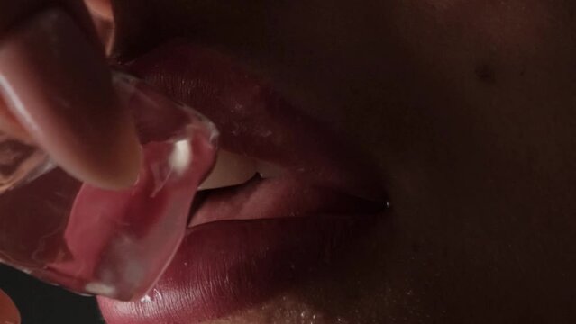 Closeup of lips with ice cube. Drops of water run down your lips. vertical video.