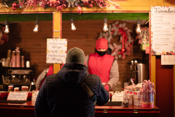 Adult man buying mulled wine at Christmas market stand.