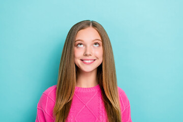 Portrait of optimistic adorable positive girl with long hairdo wear pink pullover look empty space isolated on blue color background