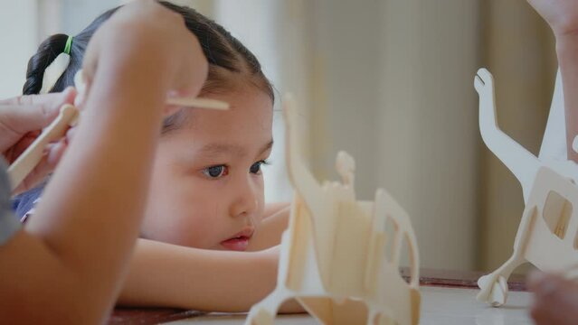 Asian little girl is modeling a wooden toy airplane with her family