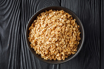 fresh raw buckwheat flakes on a black wooden background