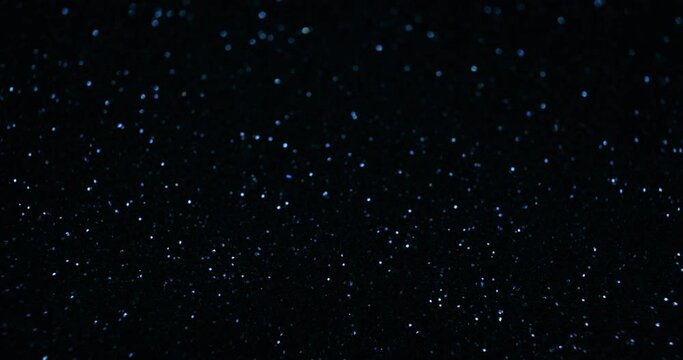 Sparkling background. Bokeh glitter texture. Defocused blue color twinkling light circles on dark night black abstract free space. Shot on RED Cinema Camera.
