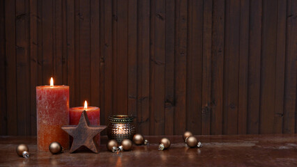 Kerzen mit Weihnachtskugeln vor einem Holzhintergrund.