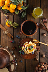 Pancakes with berries are stacked. A table with pancakes and tea on top