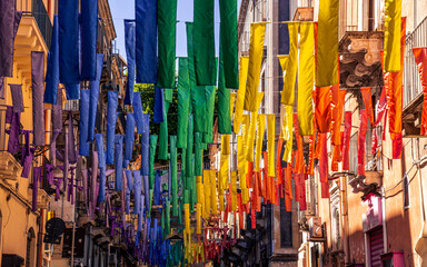 european street, decorated with hanged colorful ribbons in lgbt flag colors, city art with symbol of peace