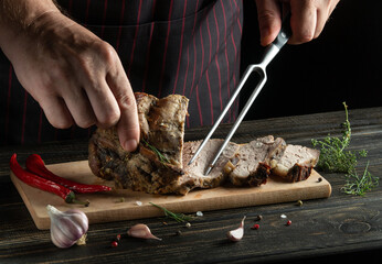 Grilled juicy beef steak. Selected marbled meat sliced on a cutting wooden board and a fork in the chef hand